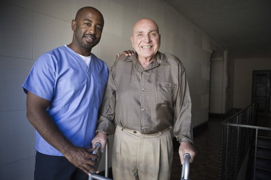 caregiver helping old man walk